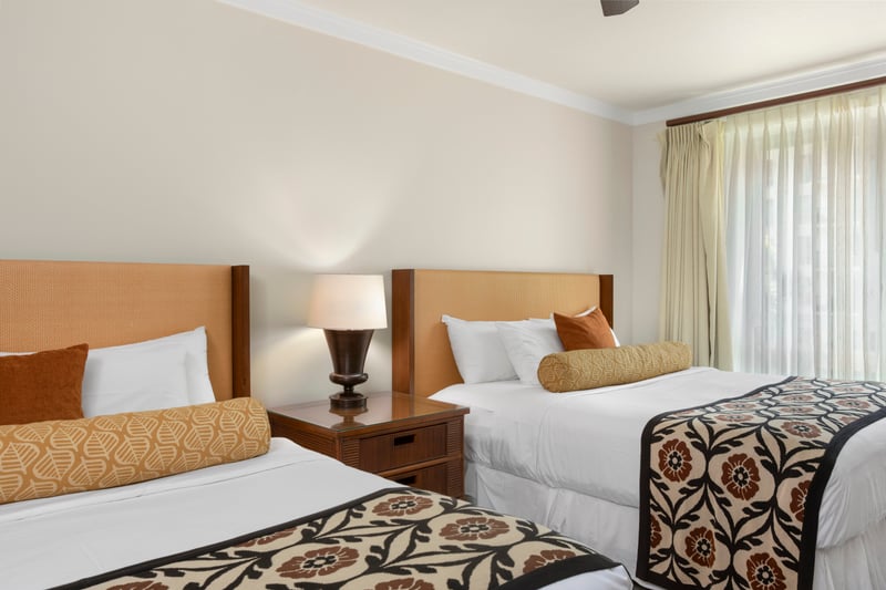 Bright guestroom with double beds, island accents, and natural light.