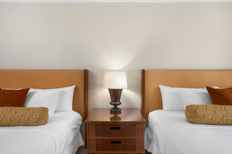Charming double guest beds with cozy linens, pillows, and warm lighting.