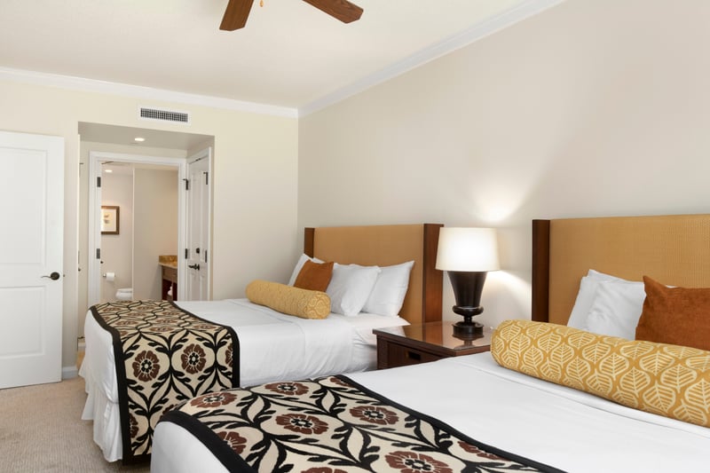 Inviting guestroom with twin beds, tropical patterns, and ensuite bathroom.