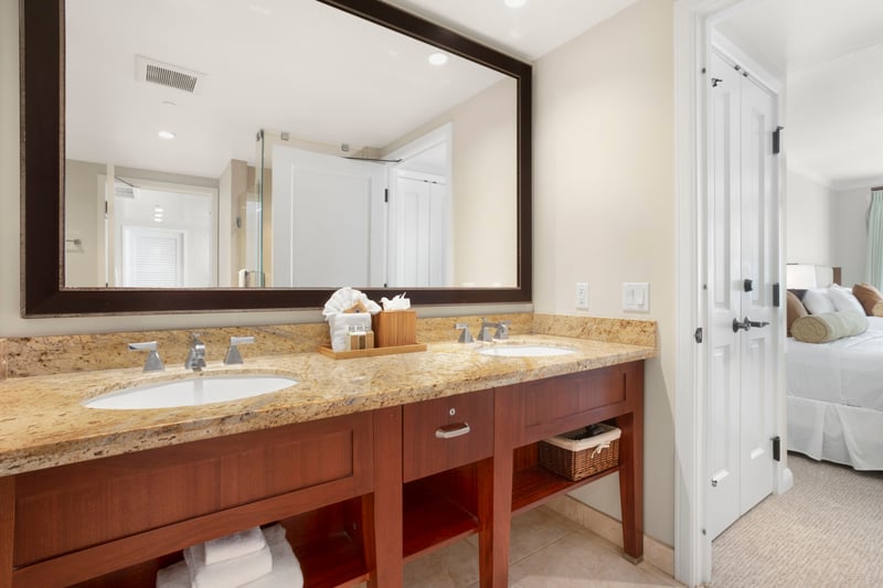 Elegant double vanity with granite top, tropical details, and suite access.