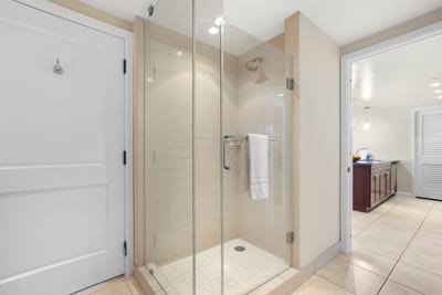 Modern glass shower with tile details, near kitchen and entryway convenience.