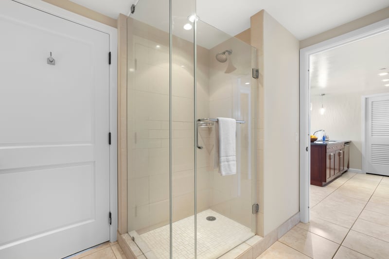 Modern glass shower with tile details, near kitchen and entryway convenience.