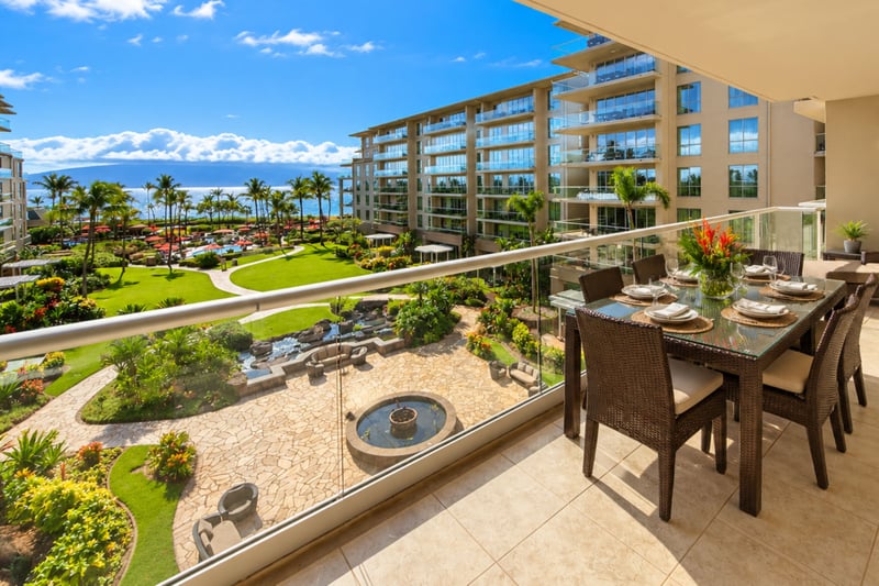 Your lanai overlooks landscaped resort grounds and a stone fountain courtyard, with a dining table set for sharing meals outdoors.