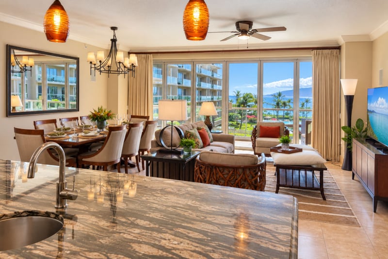 From the kitchen island, the open layout looks across the dining and living areas to sliding glass doors and the lanai beyond.