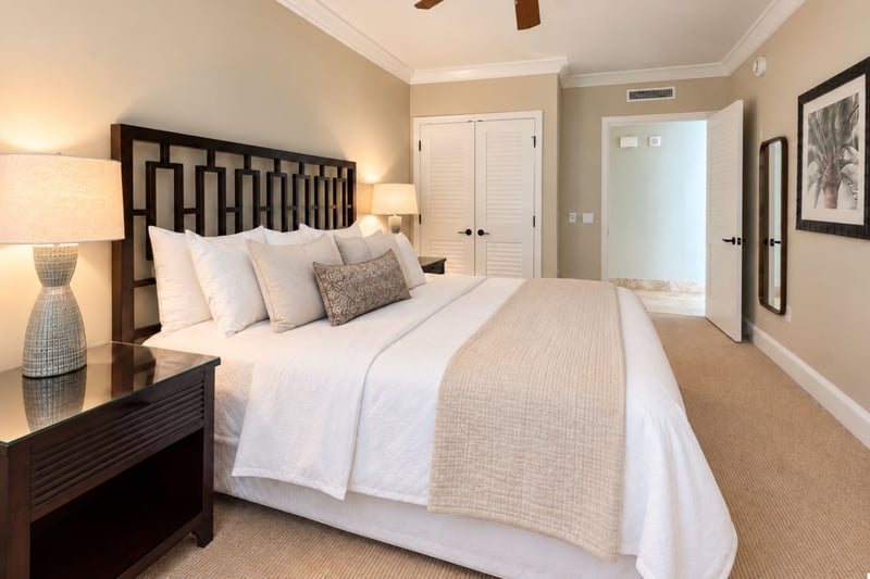 A dark wood headboard, crisp white linens and a closet with louvered doors give this bedroom a calm, uncluttered feel.