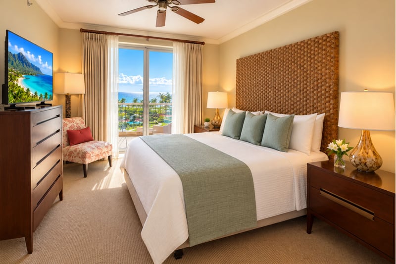 The master bedroom's king bed has a woven headboard, with sliding glass doors to the lanai, a flat screen television and a chair by the window.