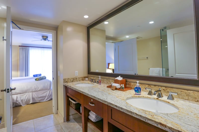 Connected bathroom with granite double vanity and bedroom suite access.