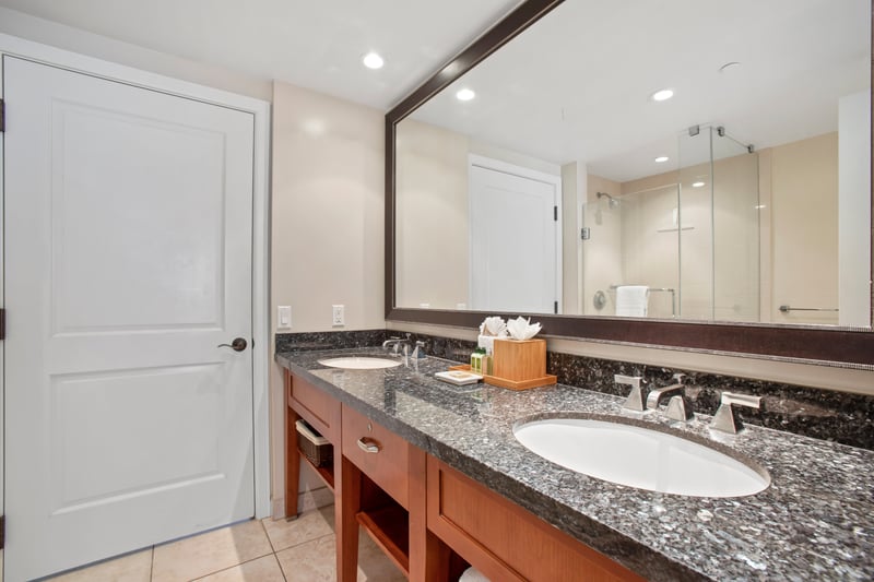 Luxury double-sink bathroom with granite countertops, glass shower, and elegance.