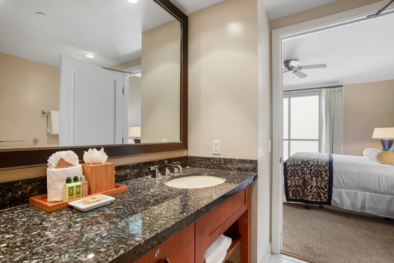 Elegant bathroom vanity with granite counter, island amenities, and bedroom view.