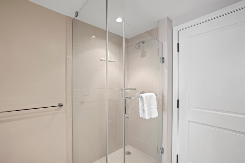 Sleek walk-in glass shower with modern fixtures and plush towel.