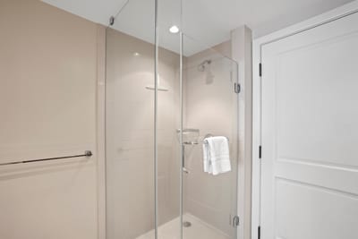 Sleek walk-in glass shower with modern fixtures and plush towel.