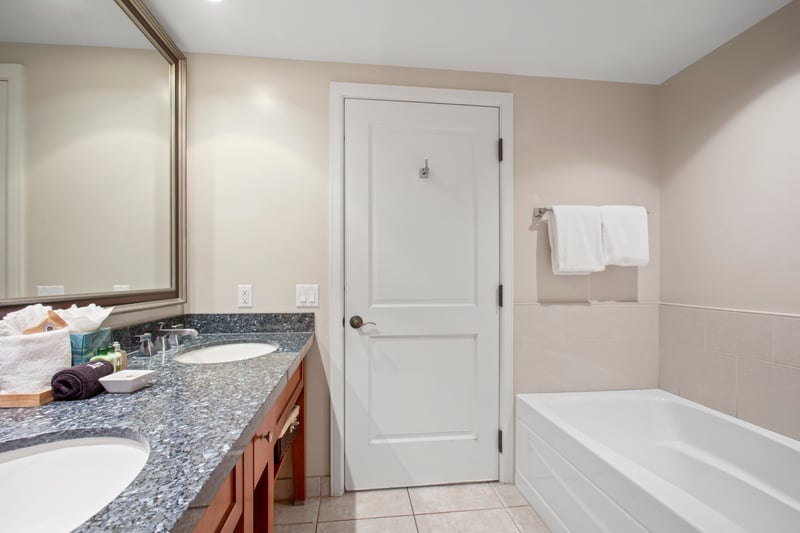 Modern bath with granite double vanity, soaking tub, and soft towels.