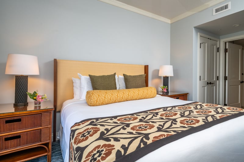 King bed detail at Honua Kai Konea 706 — tufted headboard, twin nightstands, and fresh tropical flowers