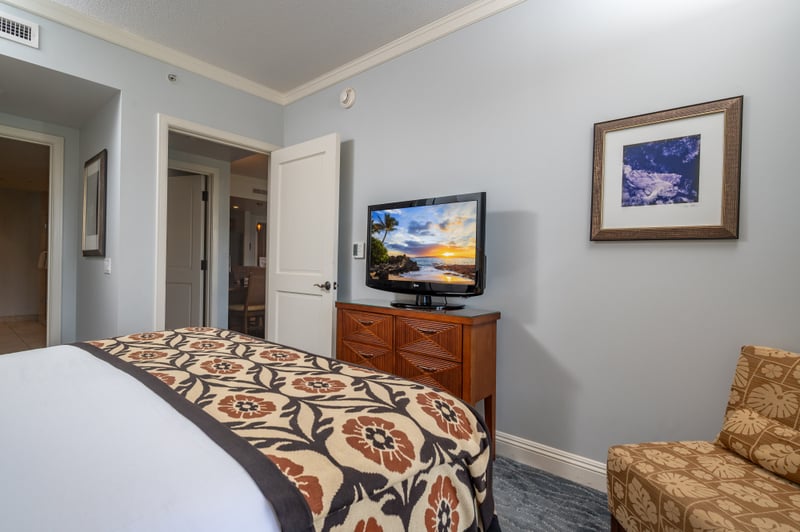 Bedroom dresser and seating area at Honua Kai Konea 706 — flat-screen TV, armchair, and local artwork