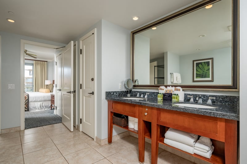 Double-sink vanity at Honua Kai Konea 706 — granite countertop, oversized mirror, and plush towels steps from the primary suite