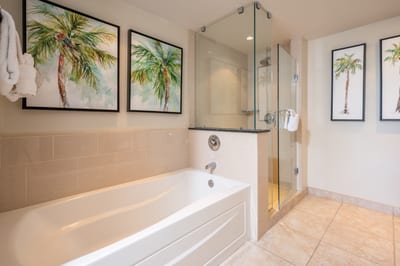 Serene palm-themed bathroom with glass shower and inviting soaking tub.