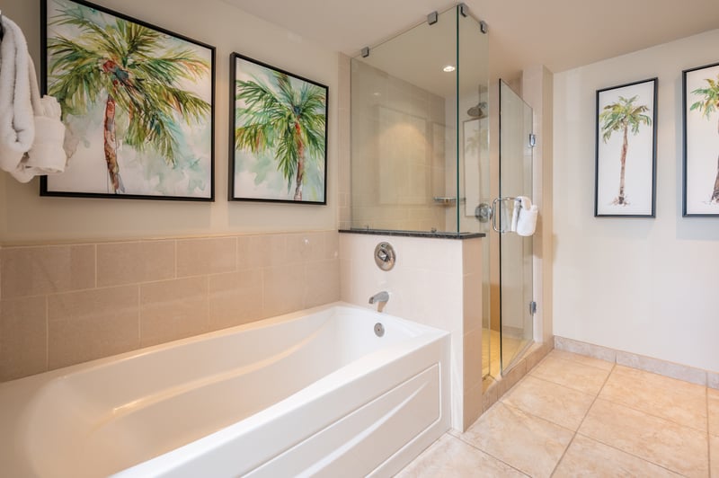 Serene palm-themed bathroom with glass shower and inviting soaking tub.