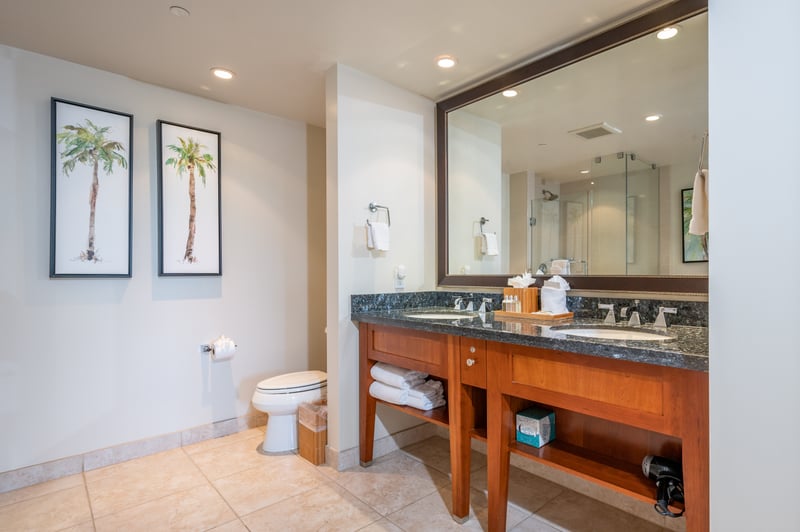 Spacious bathroom with double vanity, palm decor, and modern finishes.