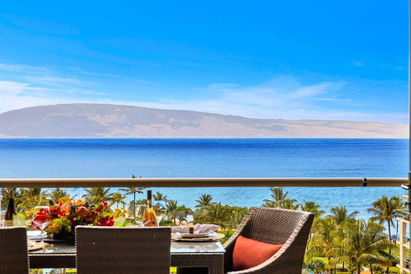 Spacious balcony with dining and lounge seating framed by sweeping ocean and garden views. HKK-825