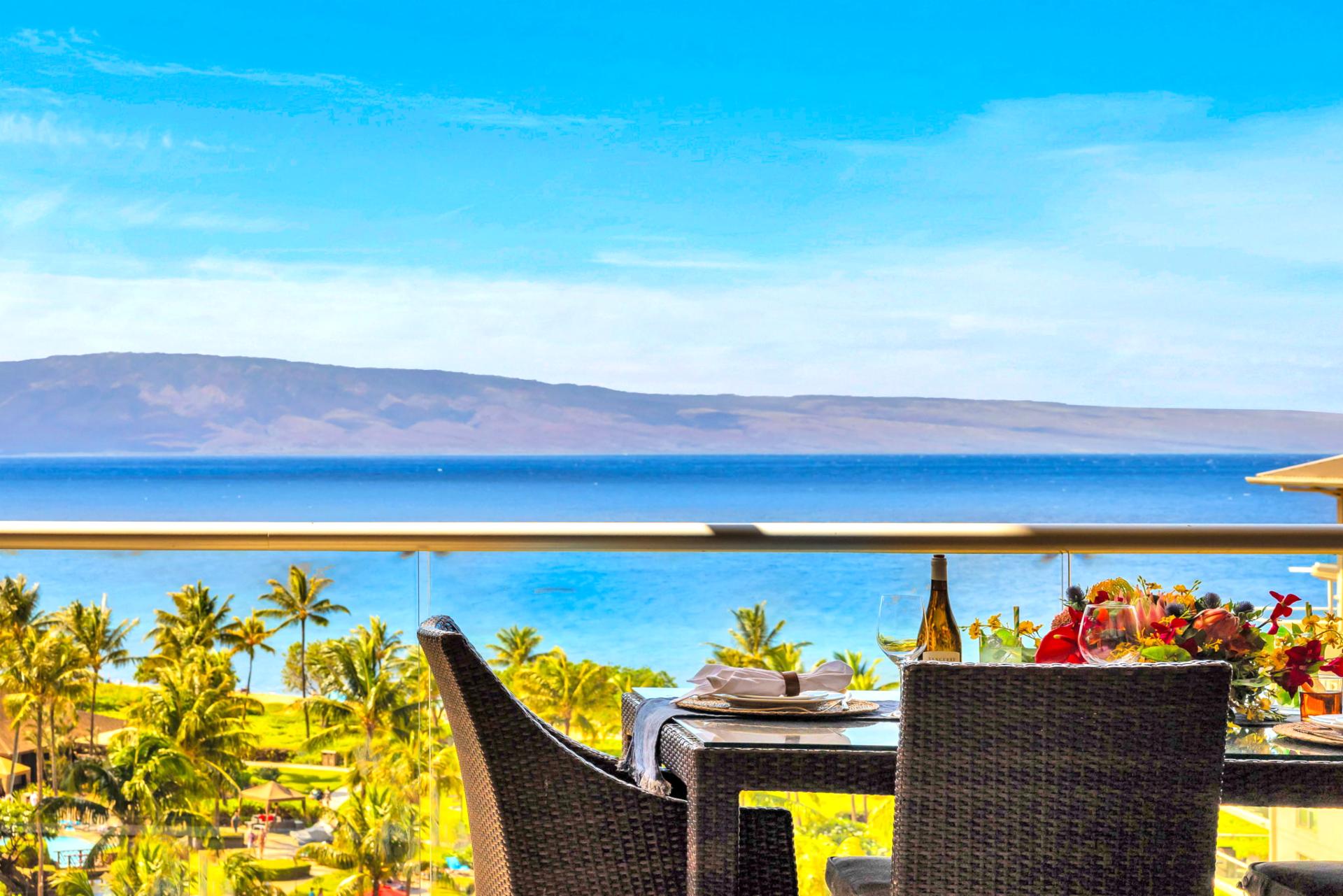 Elevated ocean view stretches over lush palms and rooftops to the sparkling blue beyond.