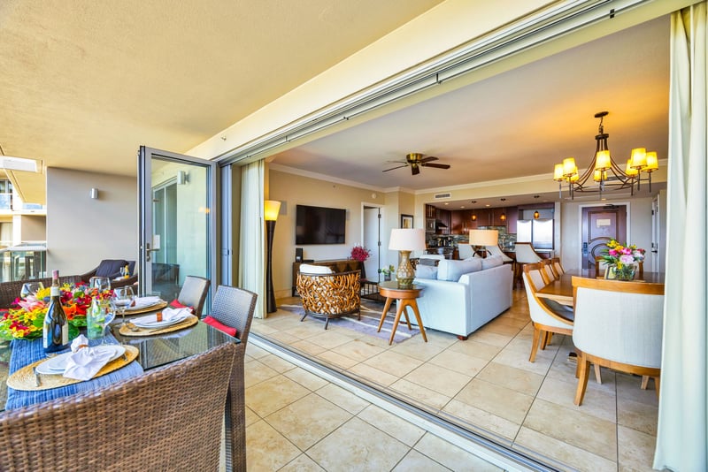 Open living layout with direct lanai access and tropical views through floor-to-ceiling glass. HKK-825