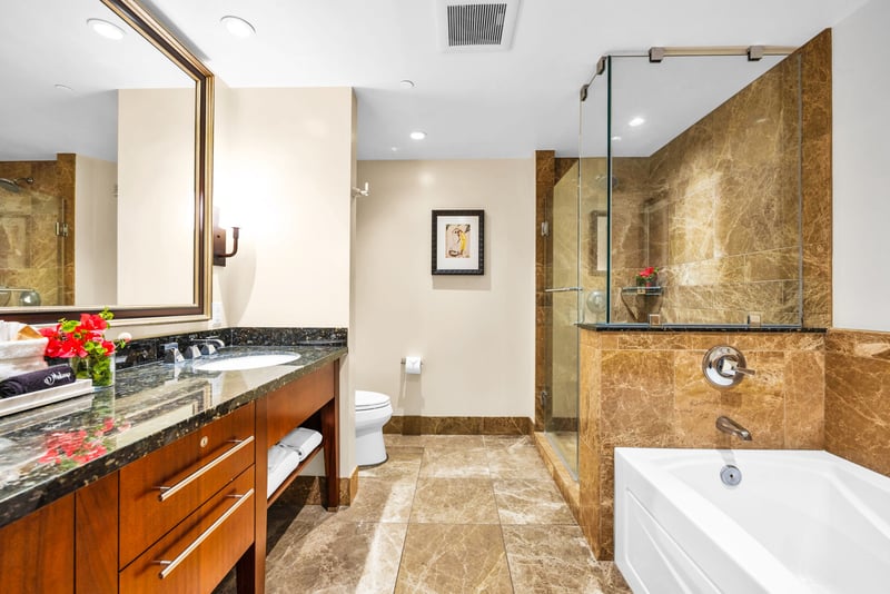 Well-lit guest bathroom with granite vanity and tiled walls.