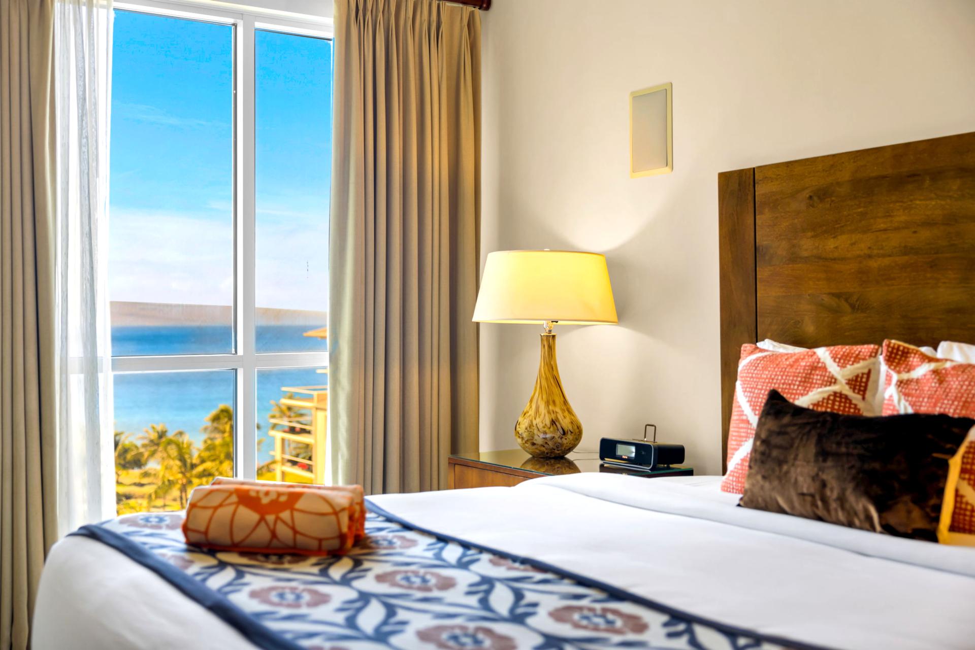 King guest bedroom with colorful island touches and ocean-facing window.