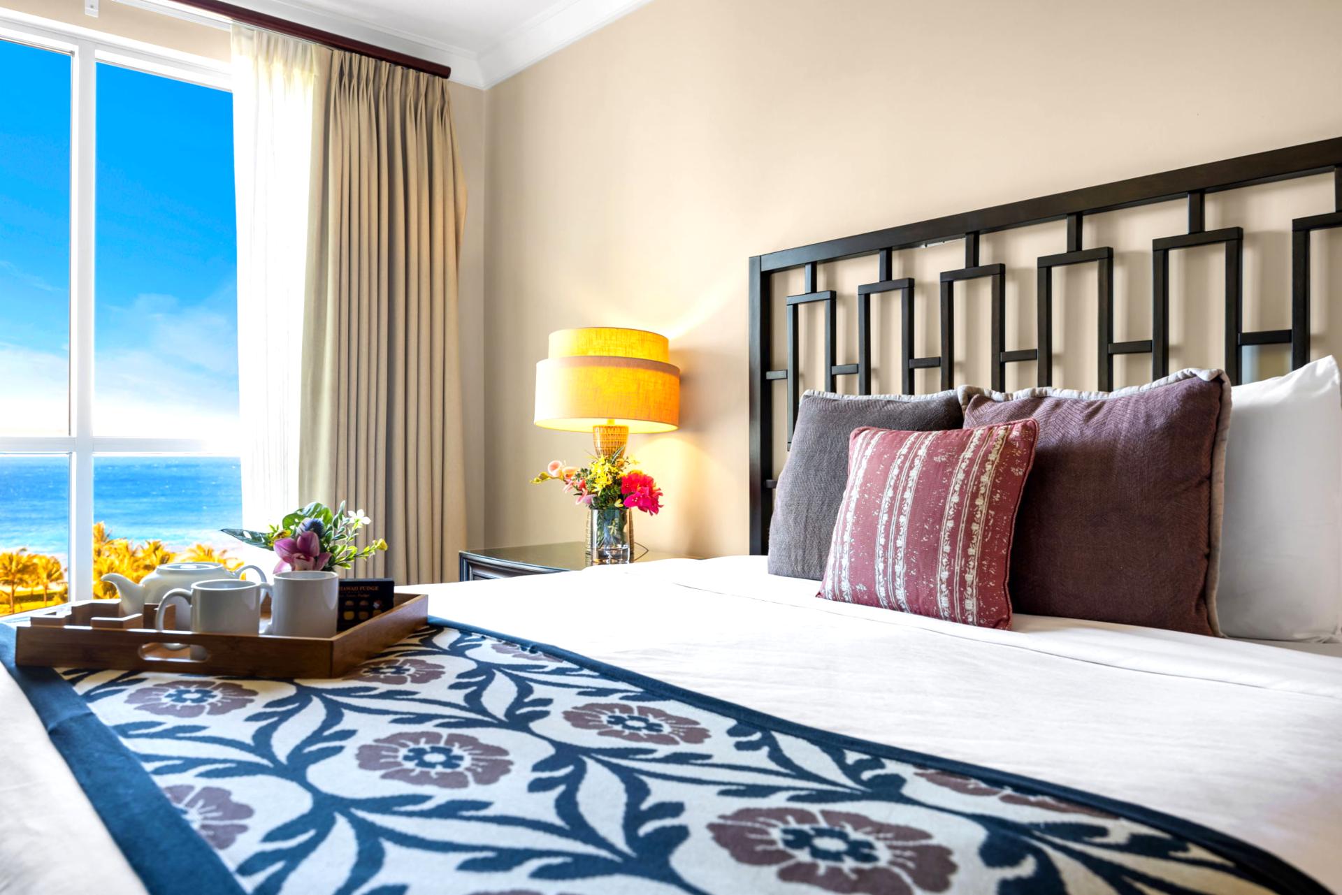 Primary bedroom with King bed, dual nightstands, and large window framing lush resort views.