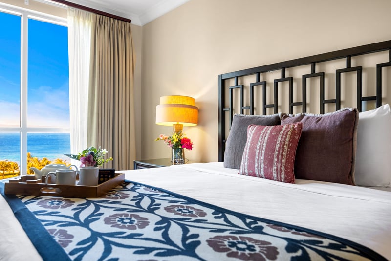 Primary bedroom with King bed, dual nightstands, and large window framing lush resort views.