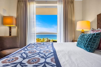 Ocean-facing guest room with King bed and plush carpeting. HKK-825