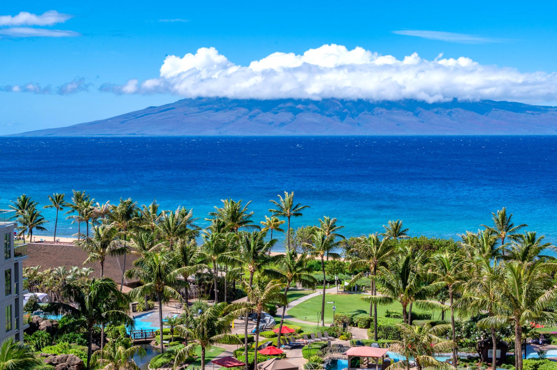 Panoramic ocean views to Molokai rise beyond the turquoise shoreline, with Honua Kai tropical pools, palms, and gardens creating a postcard-perfect foreground.