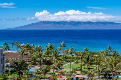 Panoramic ocean views to Molokai rise beyond the turquoise shoreline, with Honua Kai tropical pools, palms, and gardens creating a postcard-perfect foreground.