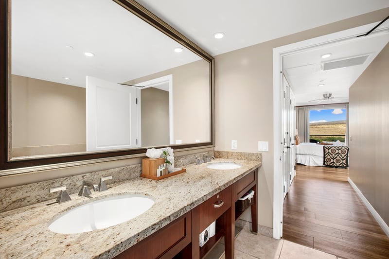 Spacious bathroom with double sinks and scenic bedroom view beyond. HKK-920