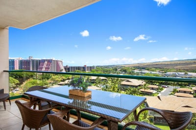 Spacious balcony dining with cityscape and lush hillside views.