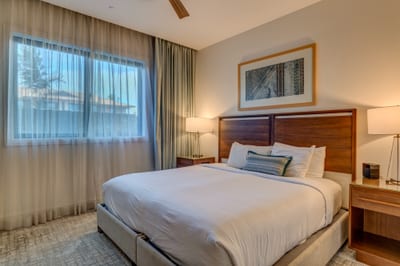 Cozy guest bedroom with king bed, plush linens and warm wood accents for a restful night's sleep