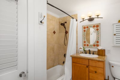 Dive into comfort with a rich tiled shower, detailed wood vanity, and whimsical décor that sparks joy with every visit