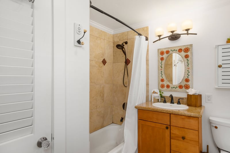 Dive into comfort with a rich tiled shower, detailed wood vanity, and whimsical décor that sparks joy with every visit