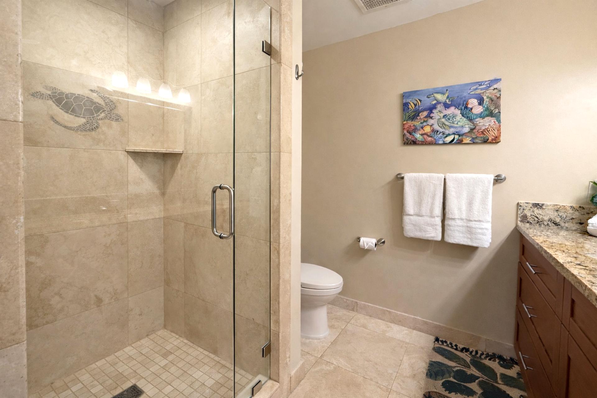 The sleek walk in shower features a decorative honu on the wall, bringing touches of the island inside