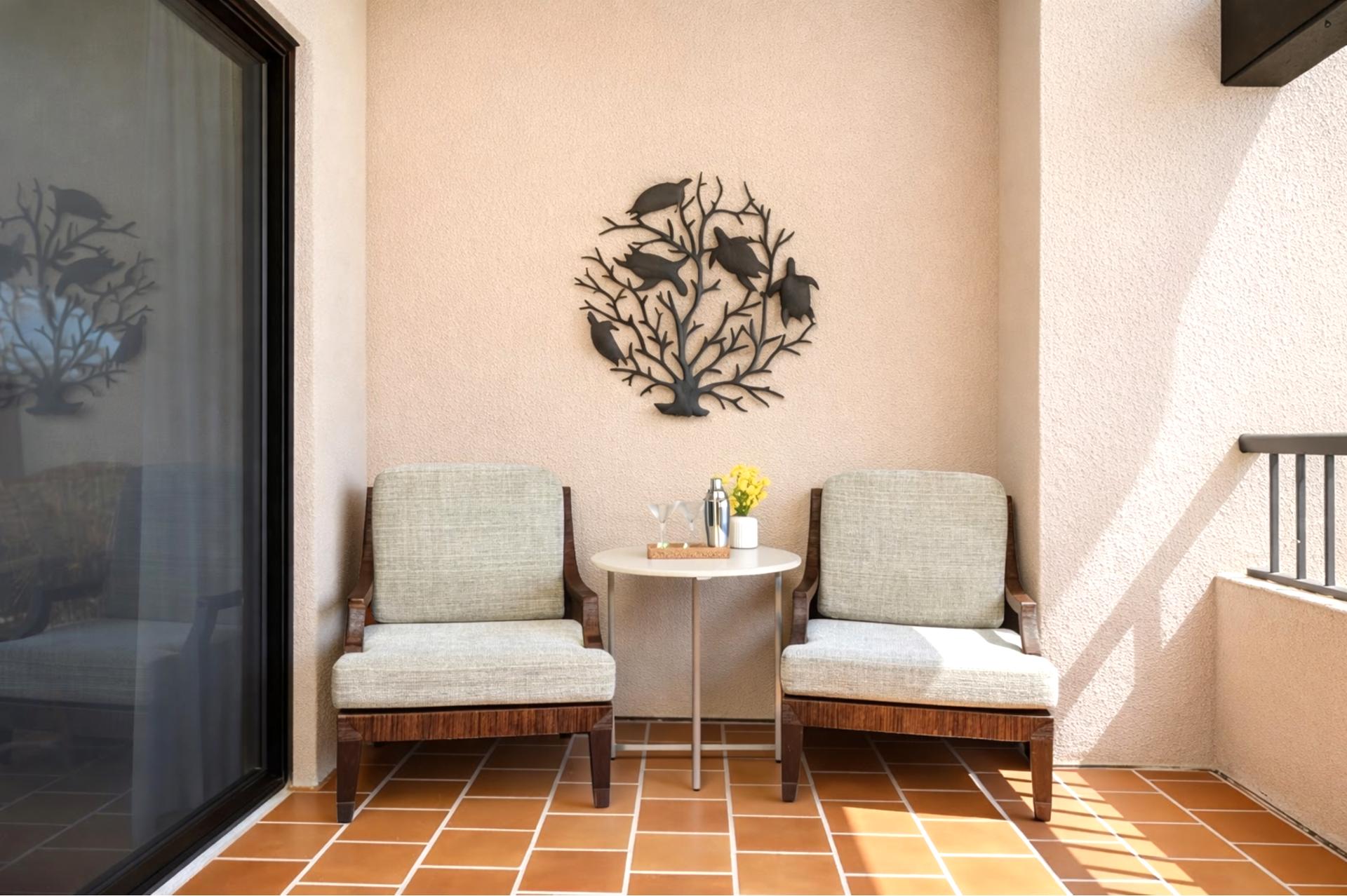 A cozy lanai nook with plush chairs and tropical wall art, perfect for morning coffee or an afternoon retreat  