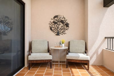A cozy lanai nook with plush chairs and tropical wall art, perfect for morning coffee or an afternoon retreat