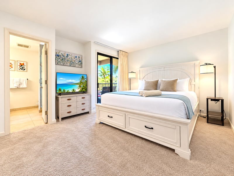 Your second bedroom features a king bed with built-in storage drawers, a TV on a dresser, and an ensuite bathroom just beside the bed.
