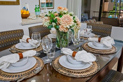 Gather beneath a palm-blade fan where petal-topped plates and woven charm make every meal feel like a keepsake
