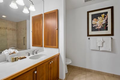 A double vanity with rich wood cabinetry and sleek white countertops anchors the space in timeless, tailored sophistication