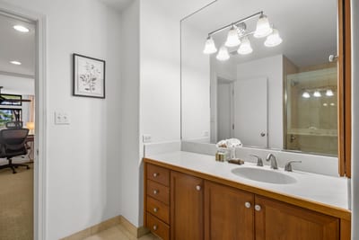 Overhead lighting reflects softly off the expansive mirror, creating a warm and balanced ambiance for daily rituals
