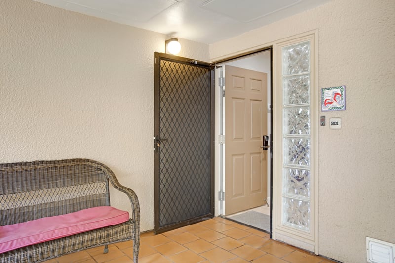 Charming private entrance with tropical tile and cozy wicker bench.
