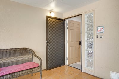 Charming private entrance with tropical tile and cozy wicker bench.