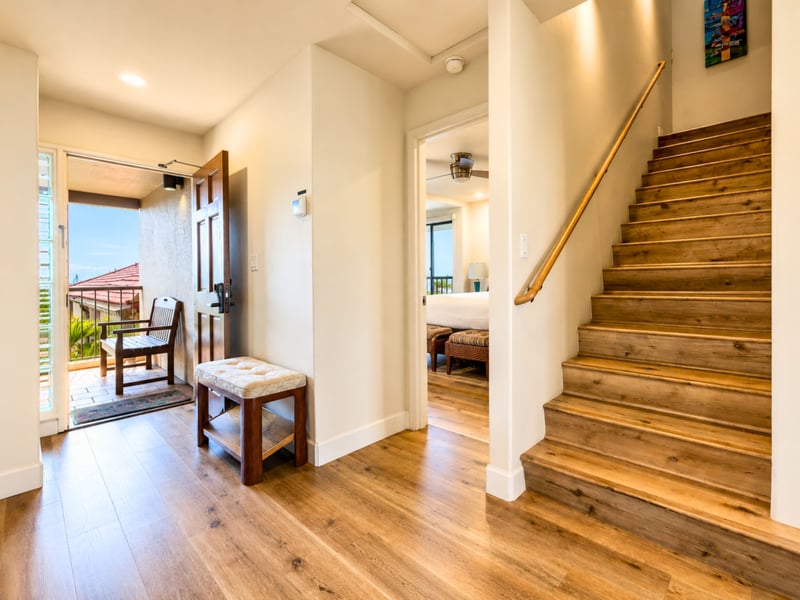 Inside the front door, wood plank flooring leads past the staircase to the living area, with the guest bedroom just off the entry.
