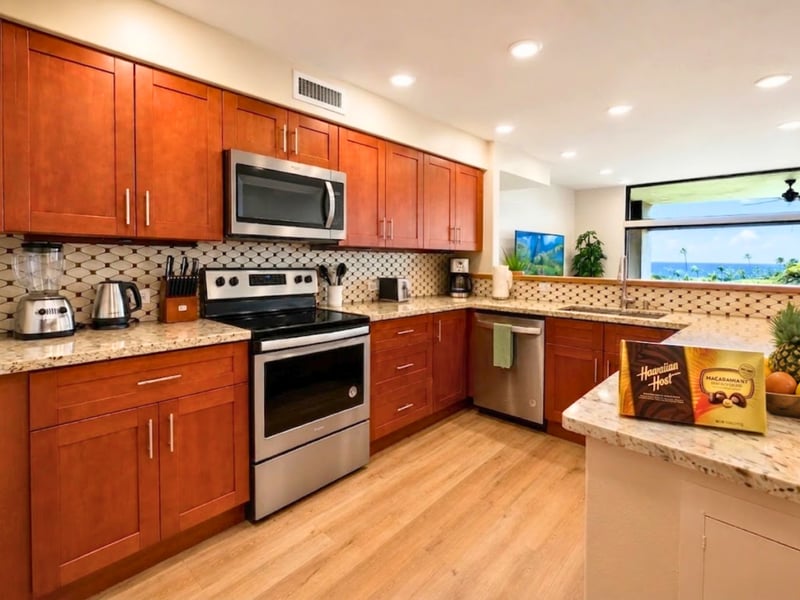 Wood cabinetry and granite counters surround a range, microwave, and dishwasher in the kitchen, giving you room to prepare meals during your stay.