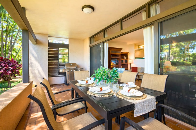 Enjoy relaxed outdoor dining on a covered lanai framed by lush gardens, with seating for six and stylish decor