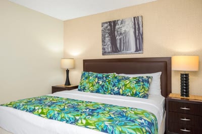 Tropical blooms meet city chic—this guest room pairs bold bedding, lanai light, and sleek storage with a smile